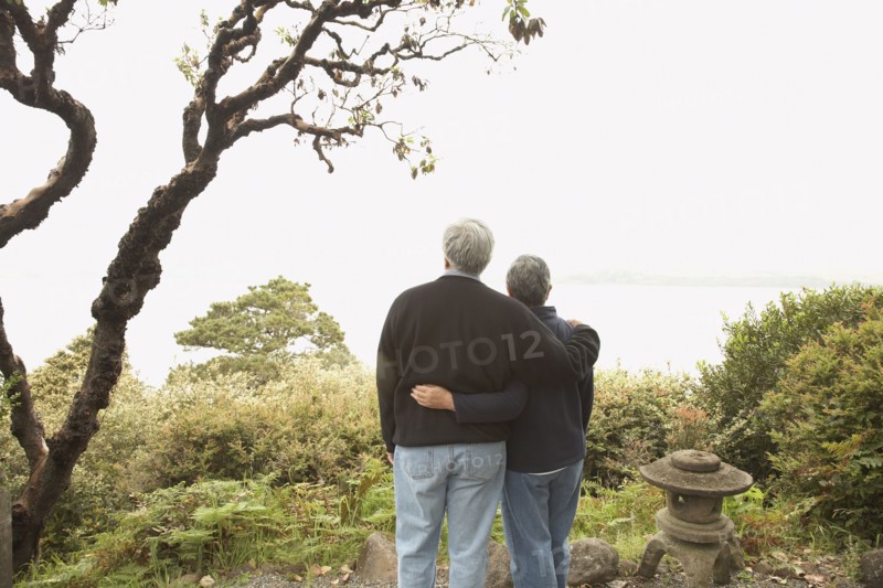 Senior couple standing arm in arm outdoors