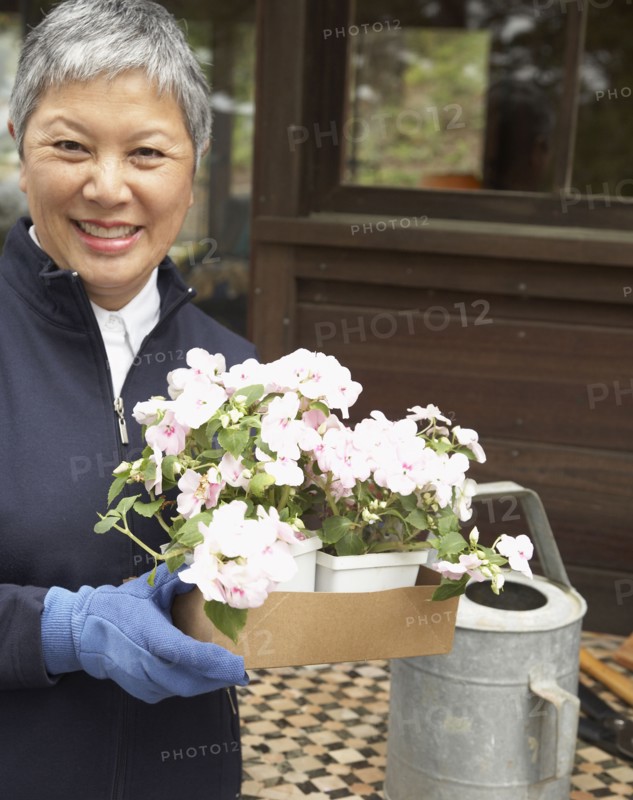 Senior Asian woman holding potted plants outdoors