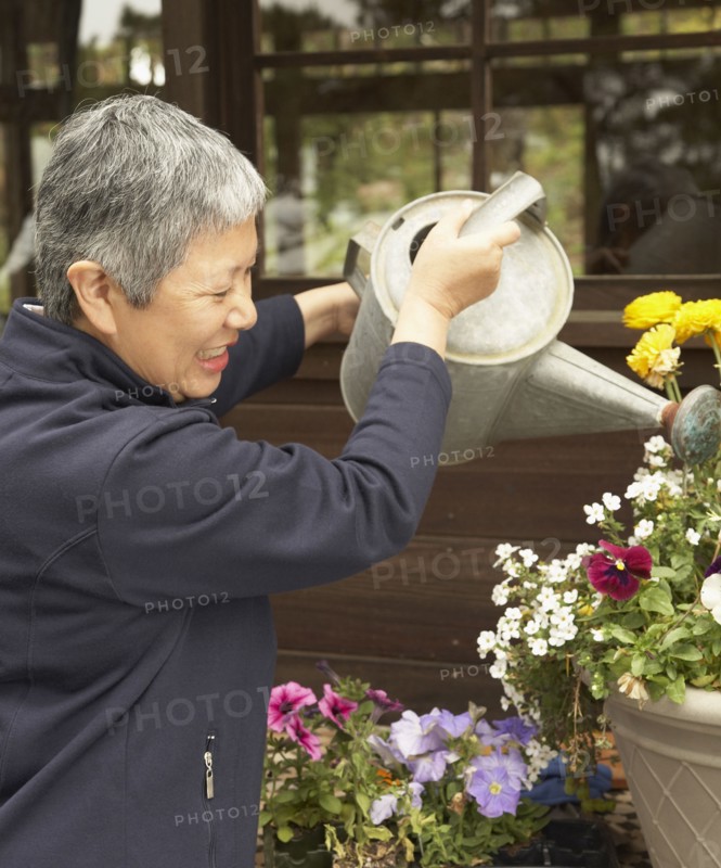 Senior Asian woman watering plants outdoors