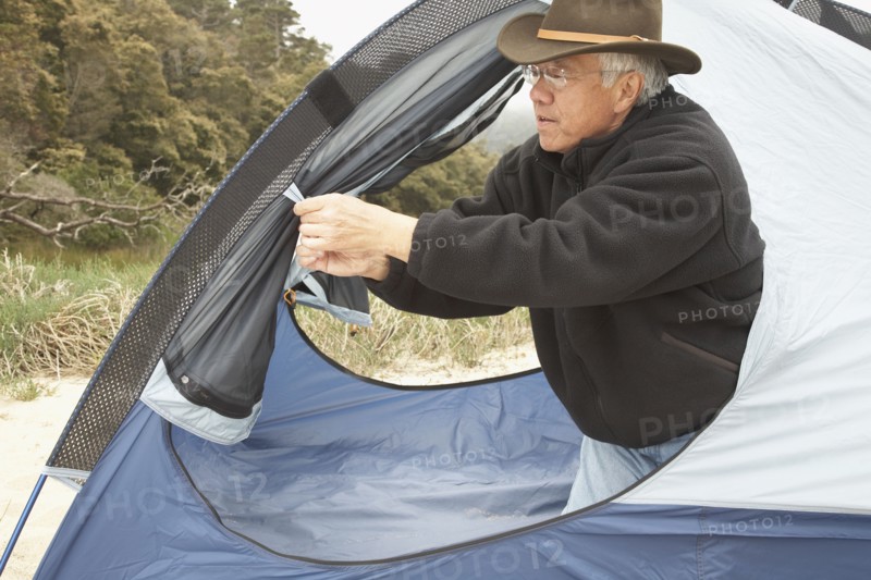 Senior Asian man opening tent