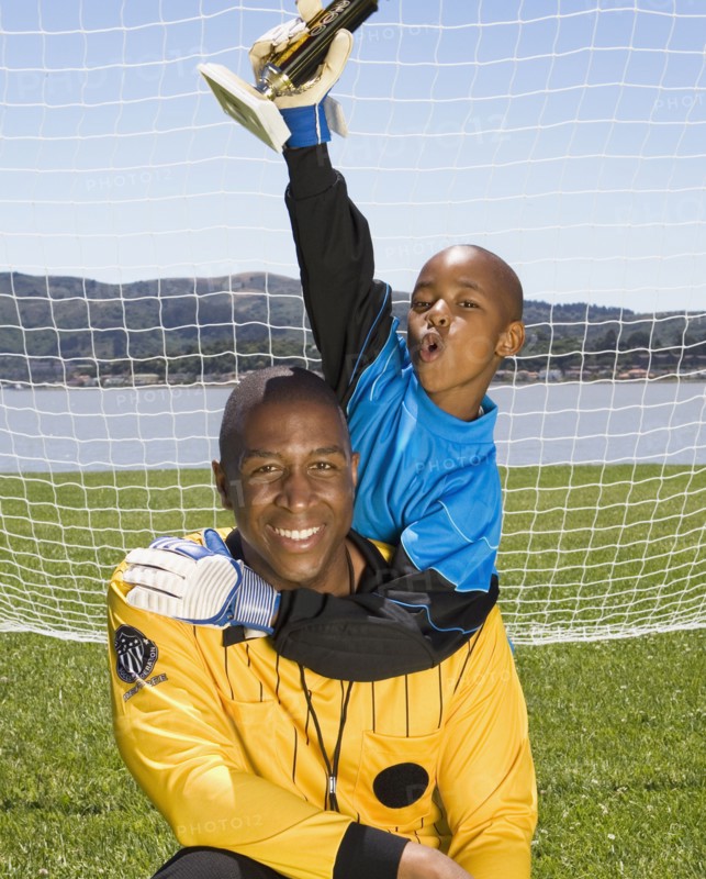 African boy and coach with soccer trophy
