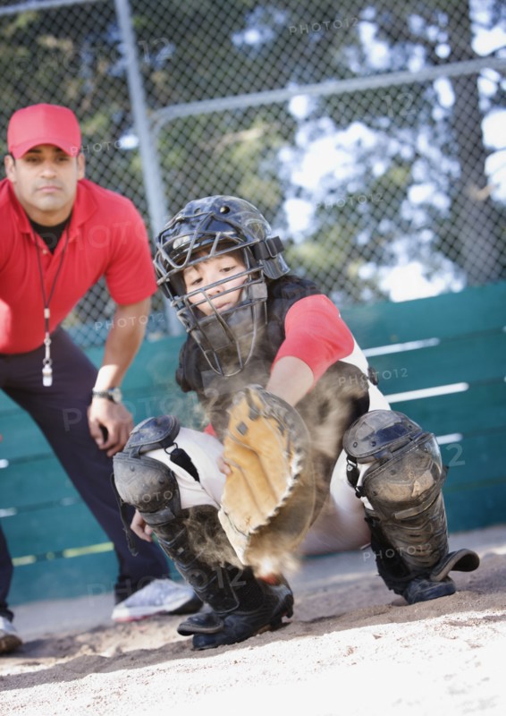 Multi-ethnic baseball catcher and coach behind home plate