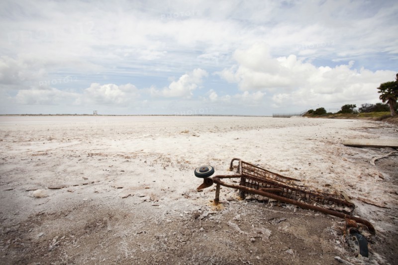 Rusted shopping cart buried in sand