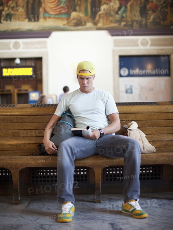 Caucasian man reading book in train station