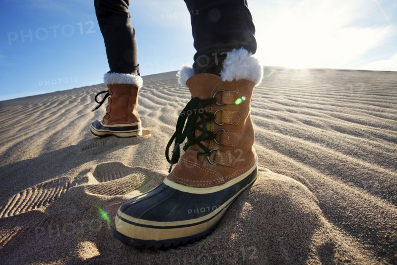 Person wearing boots standing in sand