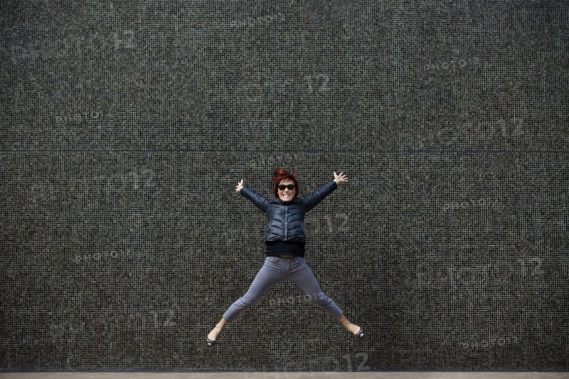 Korean woman jumping on city sidewalk