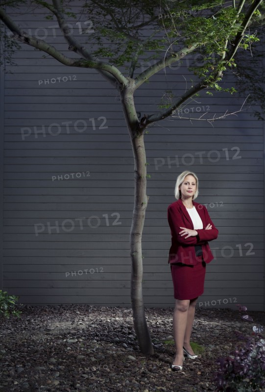 Caucasian businesswoman standing underneath tree