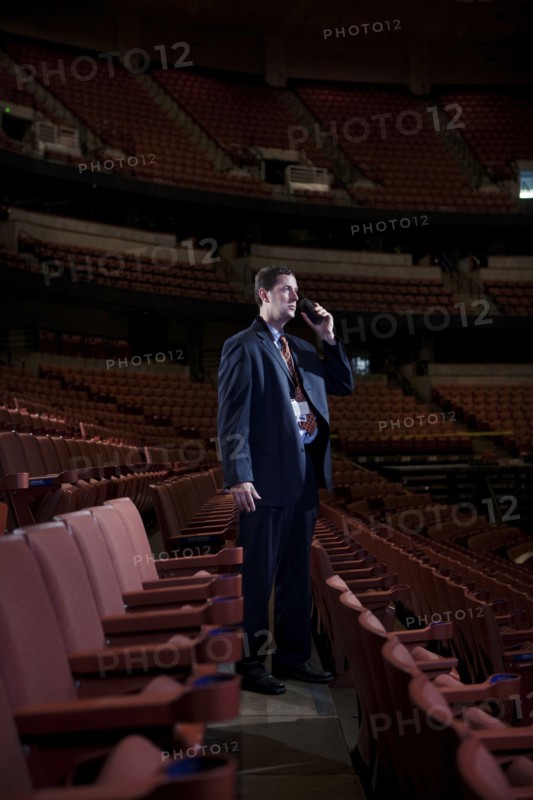 Businessman using walkie-talkie in empty auditorium
