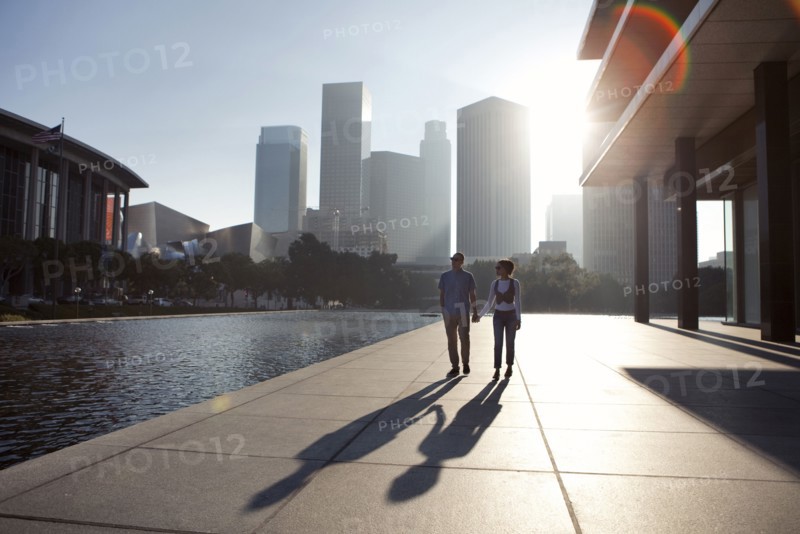 Couple casting shadows on urban waterfront