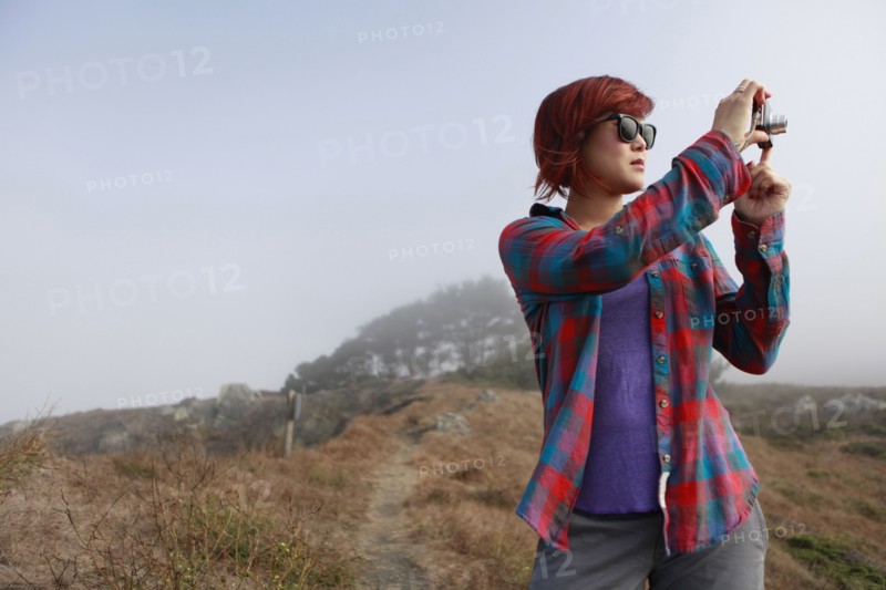 Korean woman taking photograph in remote landscape