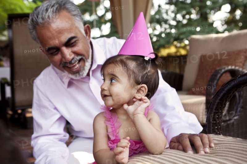 Grandfather sitting with granddaughter at birthday party