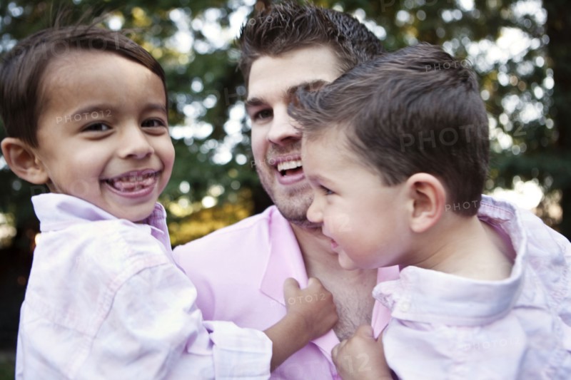 Caucasian father holding sons outdoors