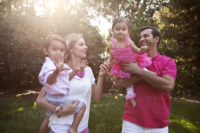 Parents holding children together in backyard