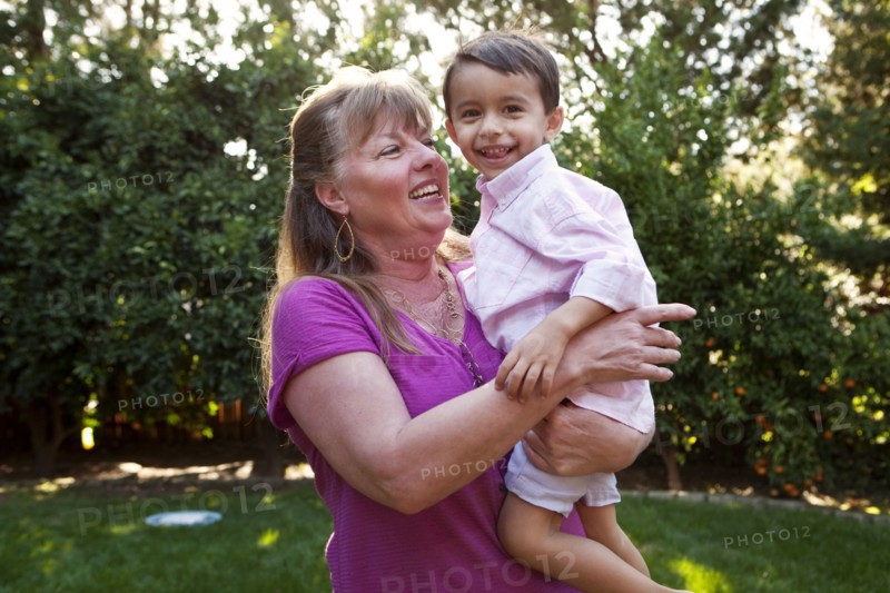 Grandmother holding grandson in backyard