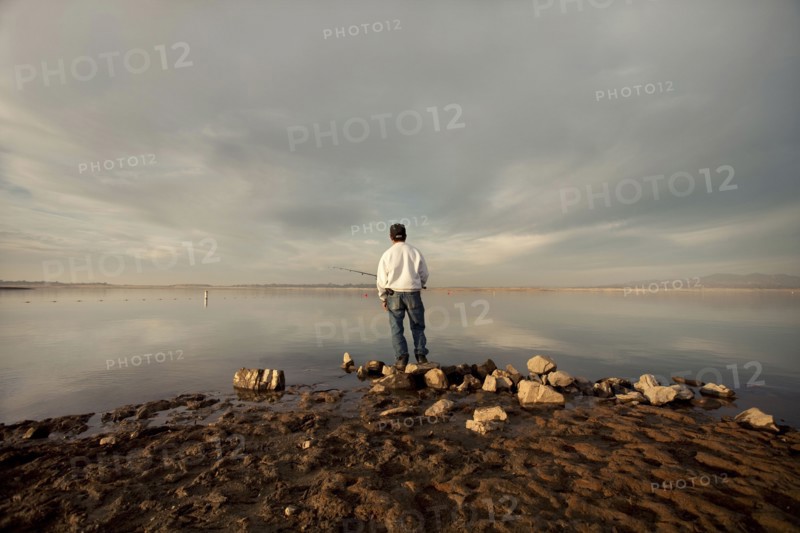 Fisherman at dry lake during drought