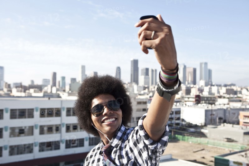 African American man taking cell phone picture from urban rooftop