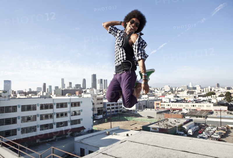 African American man jumping for joy on urban rooftop