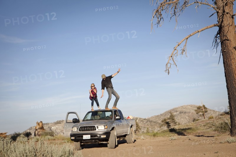 Caucasian couple standing on roof of pickup truck