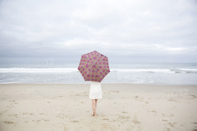 Woman standing with umbrella on beach