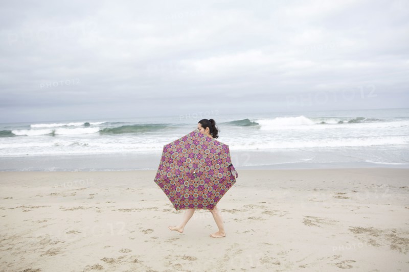 Woman walking with umbrella on beach