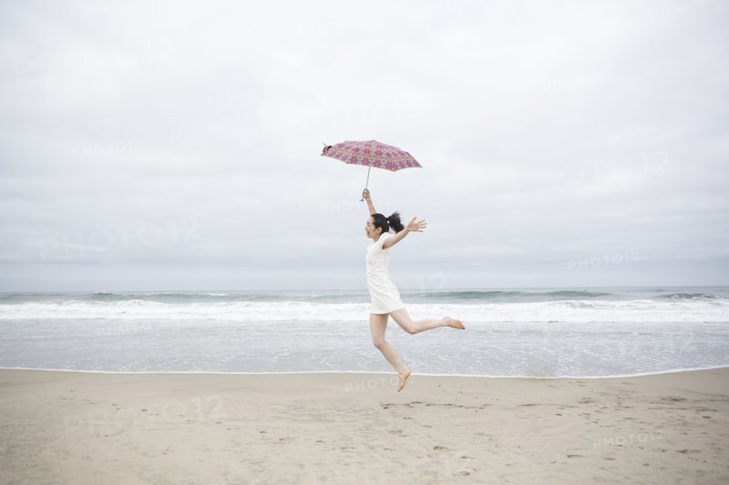 Woman playing with umbrella on beach