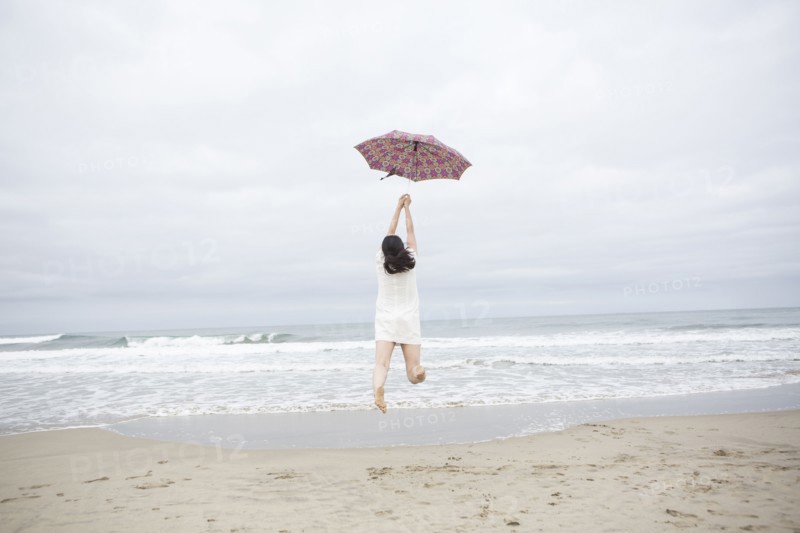 Woman playing with umbrella on beach