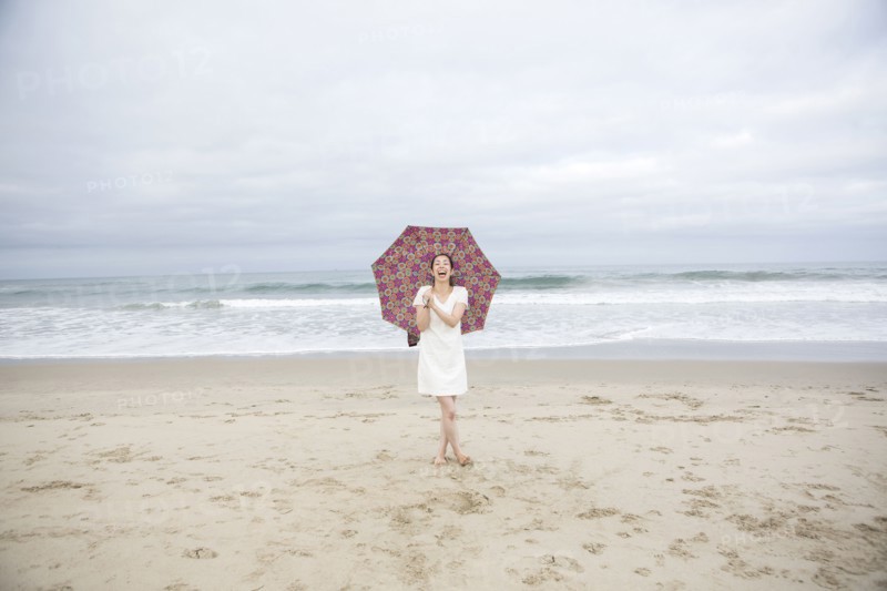 Woman laughing with umbrella on beach