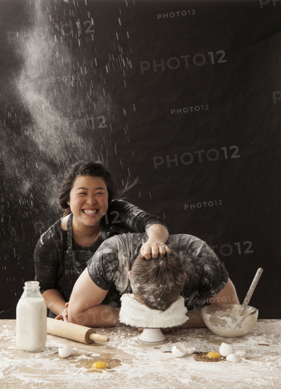 Woman shoving face of boyfriend in cake