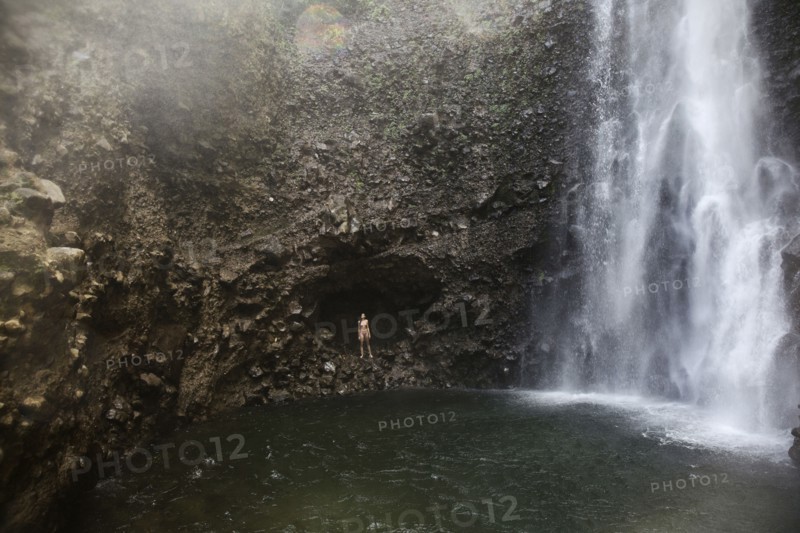 Mixed Race woman standing near waterfall pool