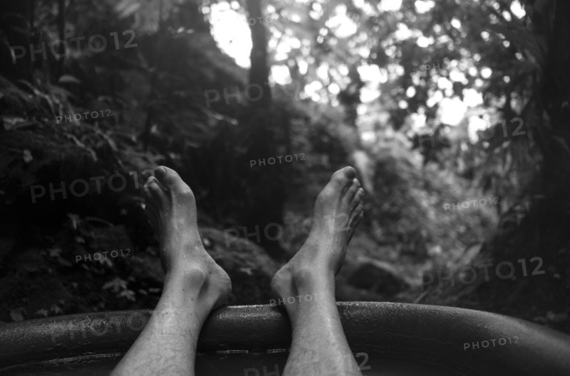 Feet of man soaking in tub outdoors