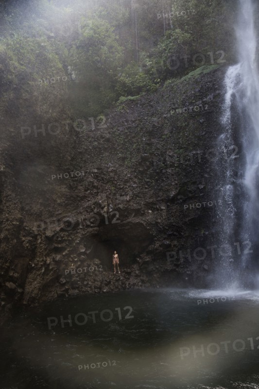 Mixed Race woman standing near waterfall pool