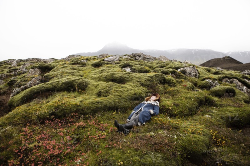 Caucasian woman laying on mossy rocks
