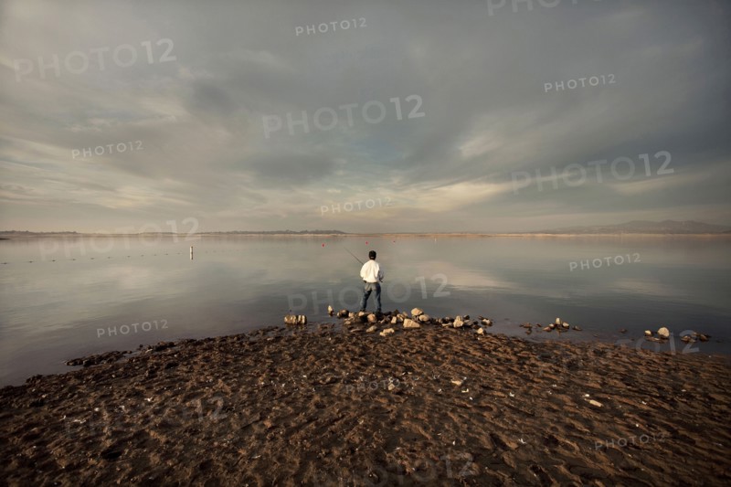Distant man fishing on beach