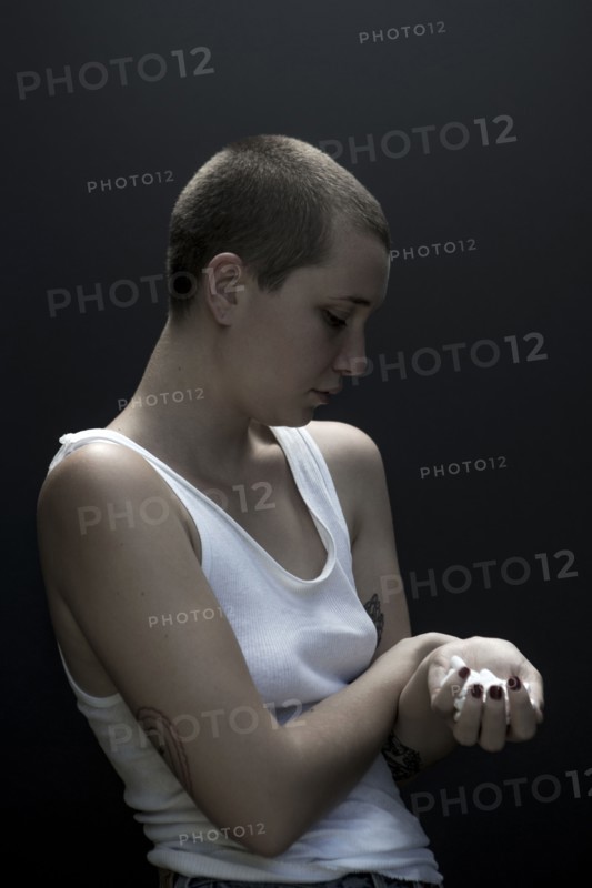 Serious Caucasian woman with shaved-head holding pills