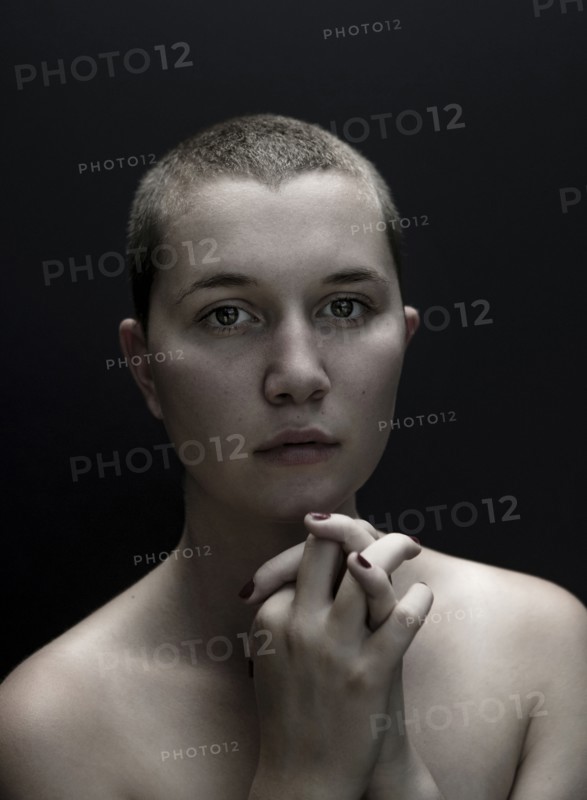 Portrait of serious Caucasian woman with shaved-head and hands clasped