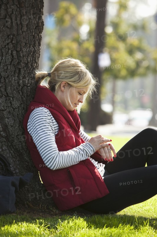 Caucasian woman leaning against tree in park