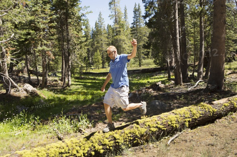 Man walking on log in forest
