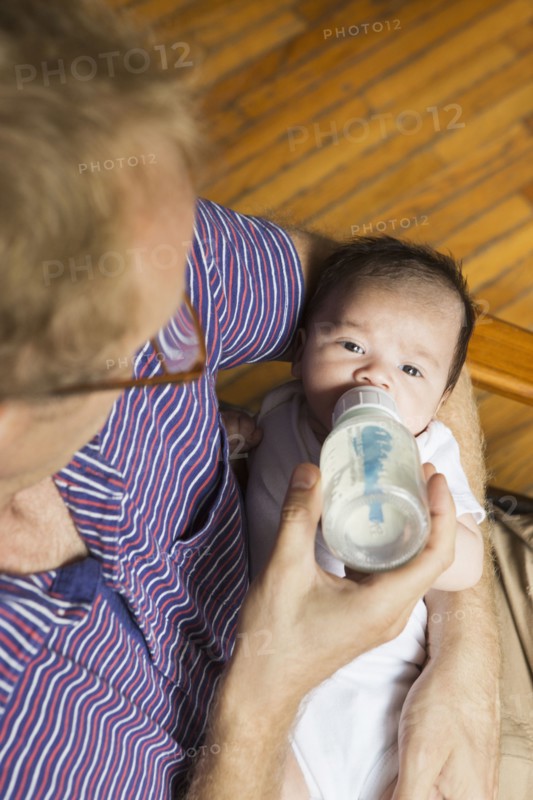 High angle view of father bottle feeding baby