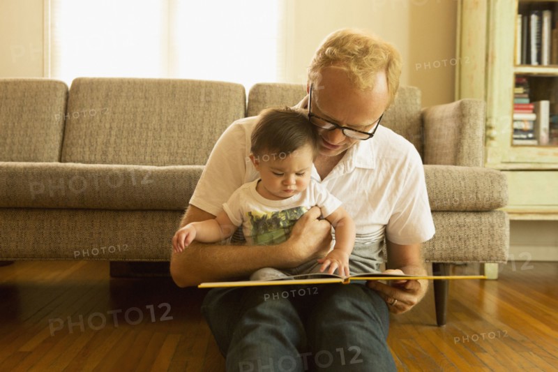 Father reading to son on living room floor
