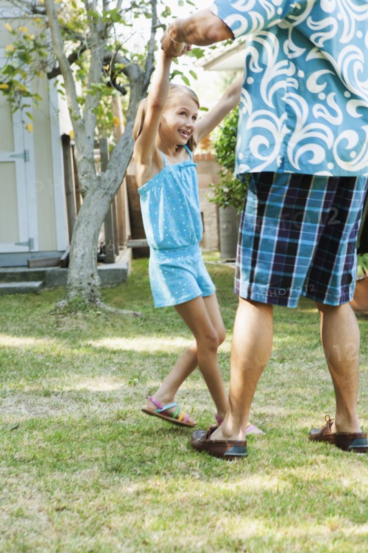 Father and daughter dancing in backyard