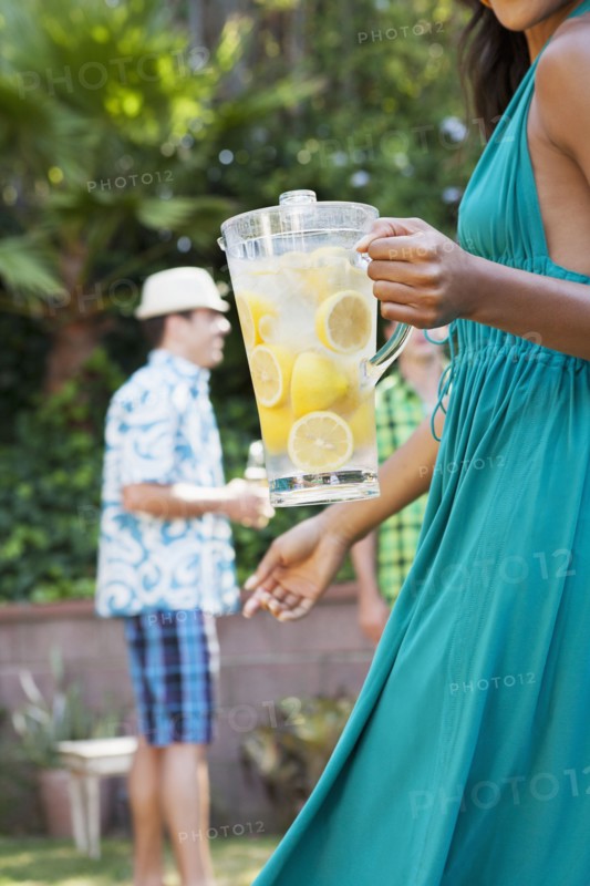 Woman holding pitcher of lemonade at backyard barbecue