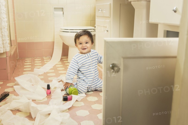 Baby boy playing in messy bathroom