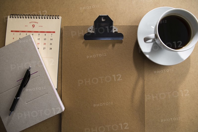 Clipboard and notepad with coffee on table
