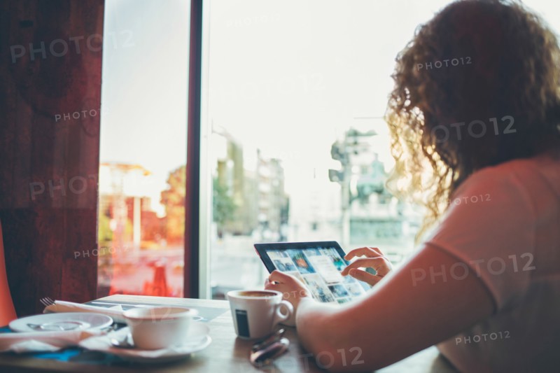 Woman using tablet computer in cafe