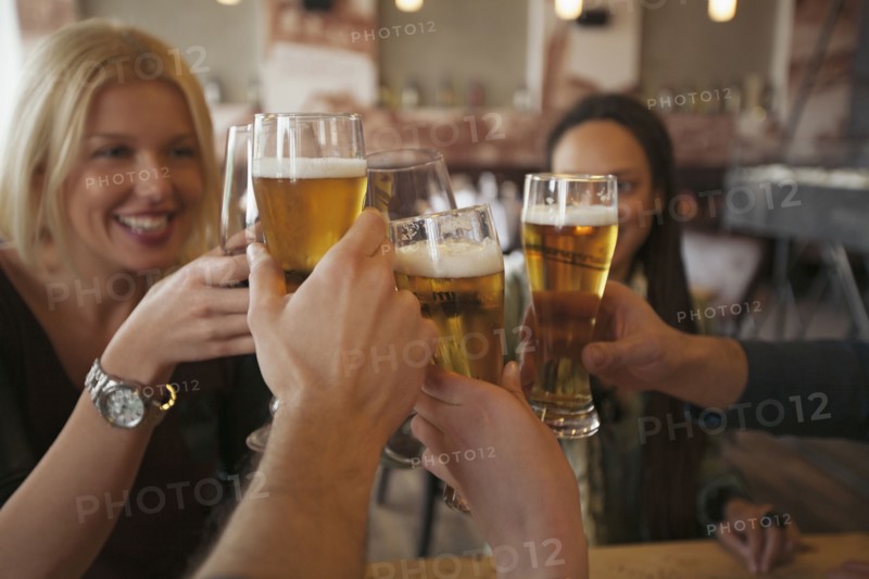 Friends toasting with beer in cafe