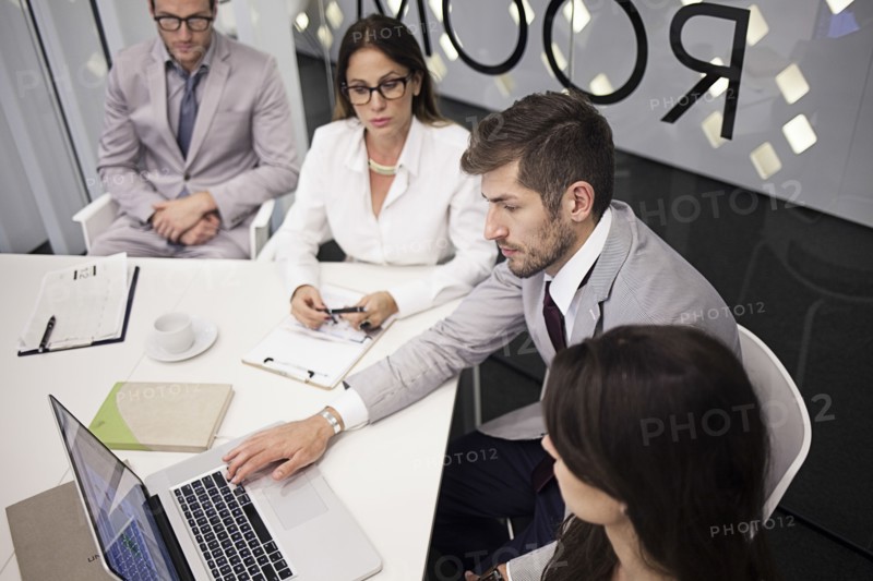 Caucasian business people using laptop in office meeting