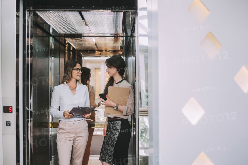 Caucasian businesswomen talking in elevator