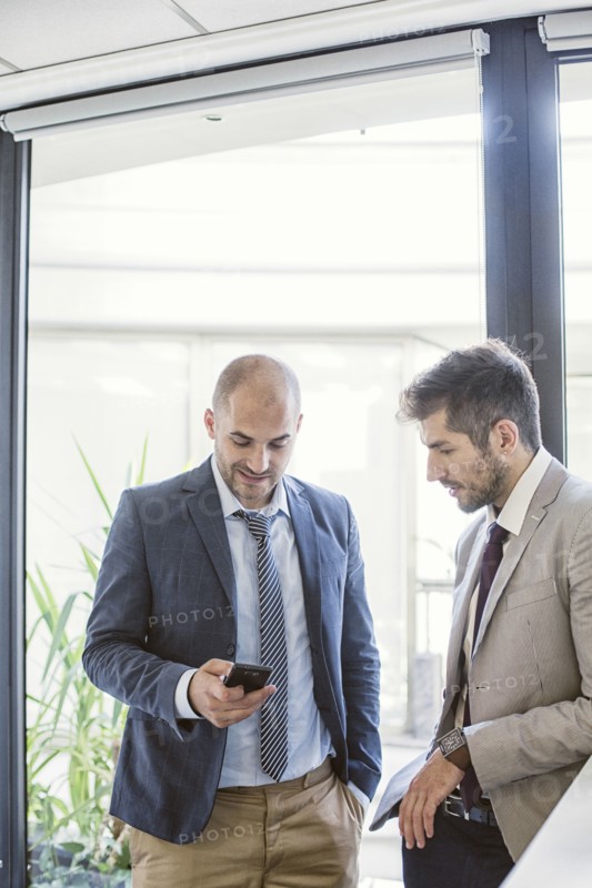 Caucasian businessmen using cell phone in office lobby