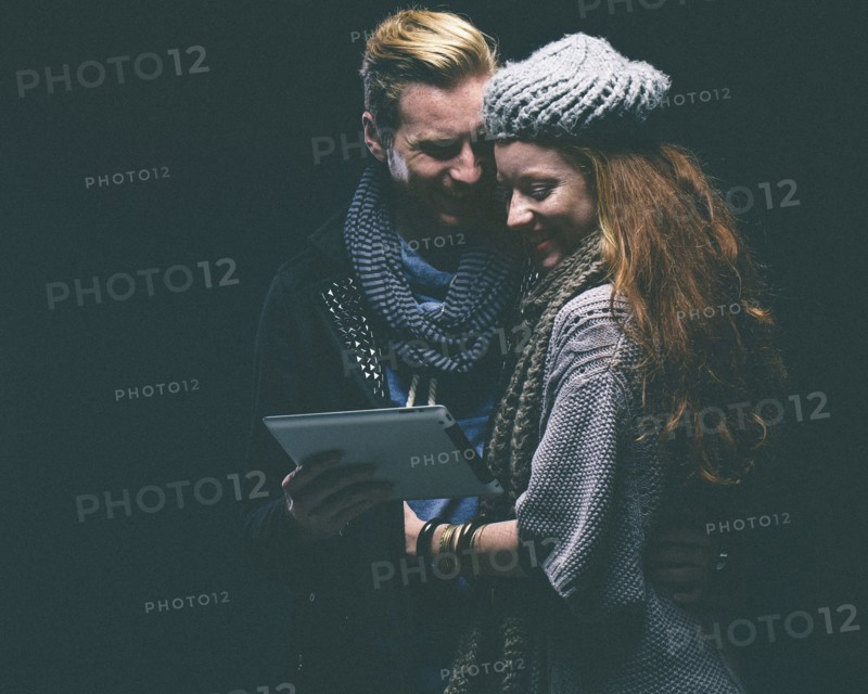 Couple wearing warm clothing using digital tablet
