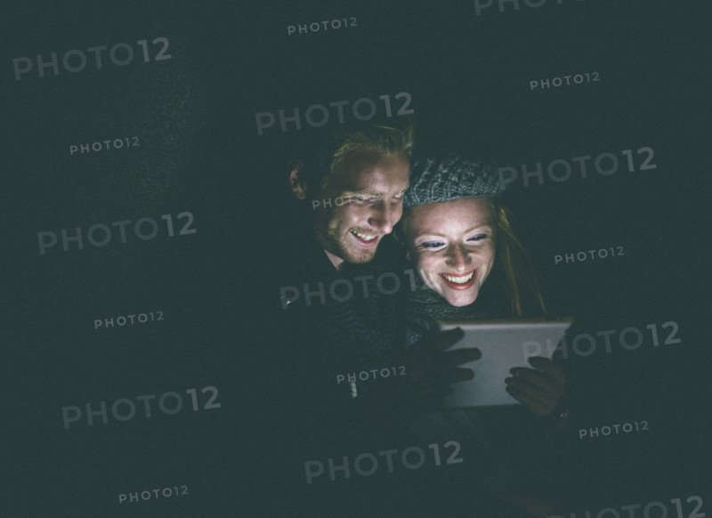 Couple wearing warm clothing using digital tablet at night